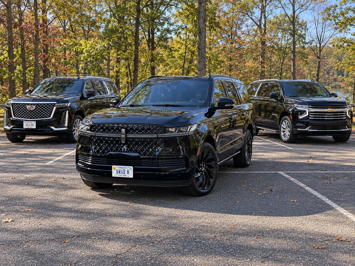 Client-reference Lincoln Navigator L in front of the Cadillac Escalade and 2026 Suburban at a wooded Fairfax County parking area